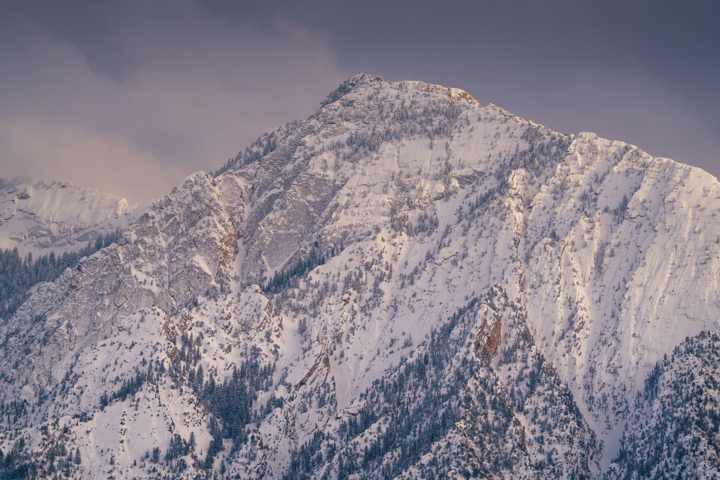 Snow-covered Wasatch peak under a muted overcast sky